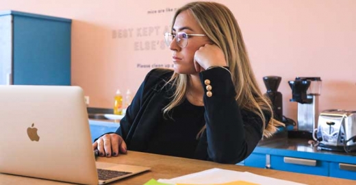 Bespectacled woman sitting in front of a laptop